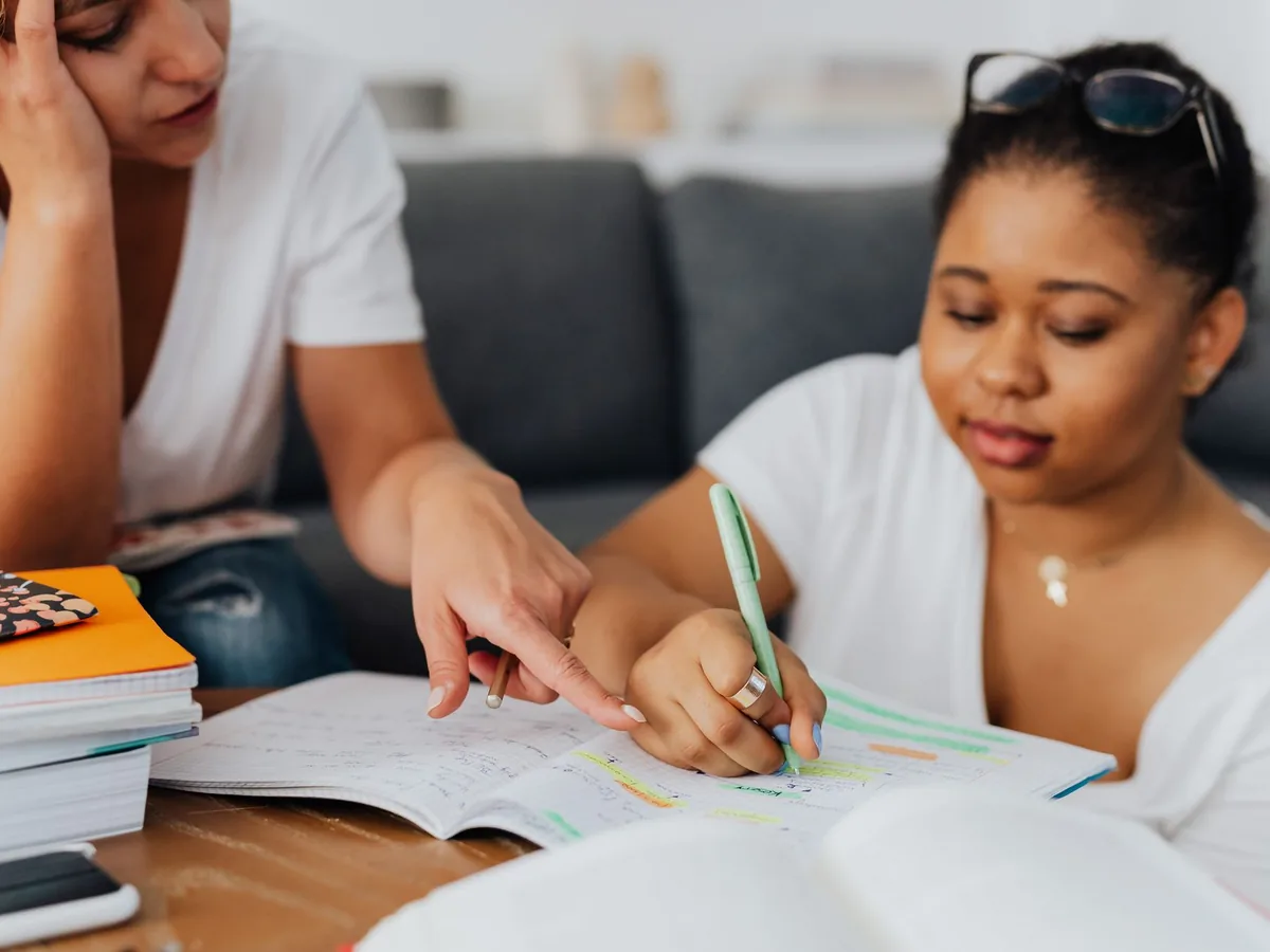 Tutora acompañando a una estudiante con sus cuadernos en casa